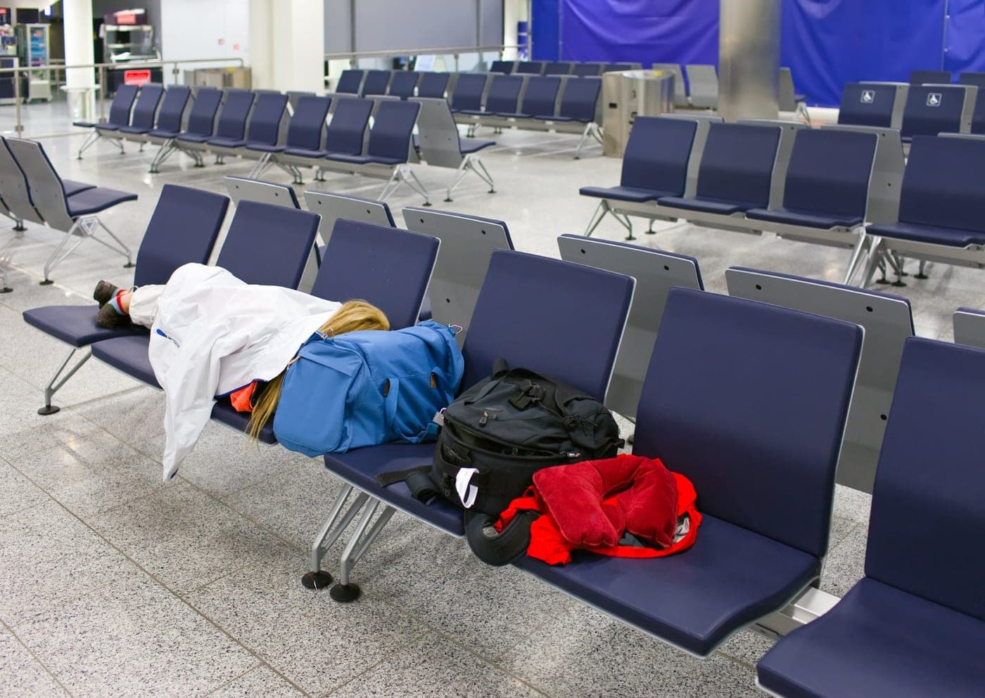 A traveller asleep across airport seats